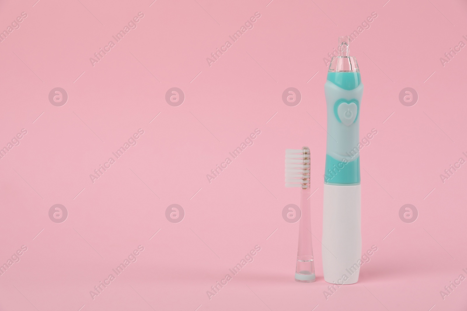 Photo of Electric toothbrush on pink background, space for text