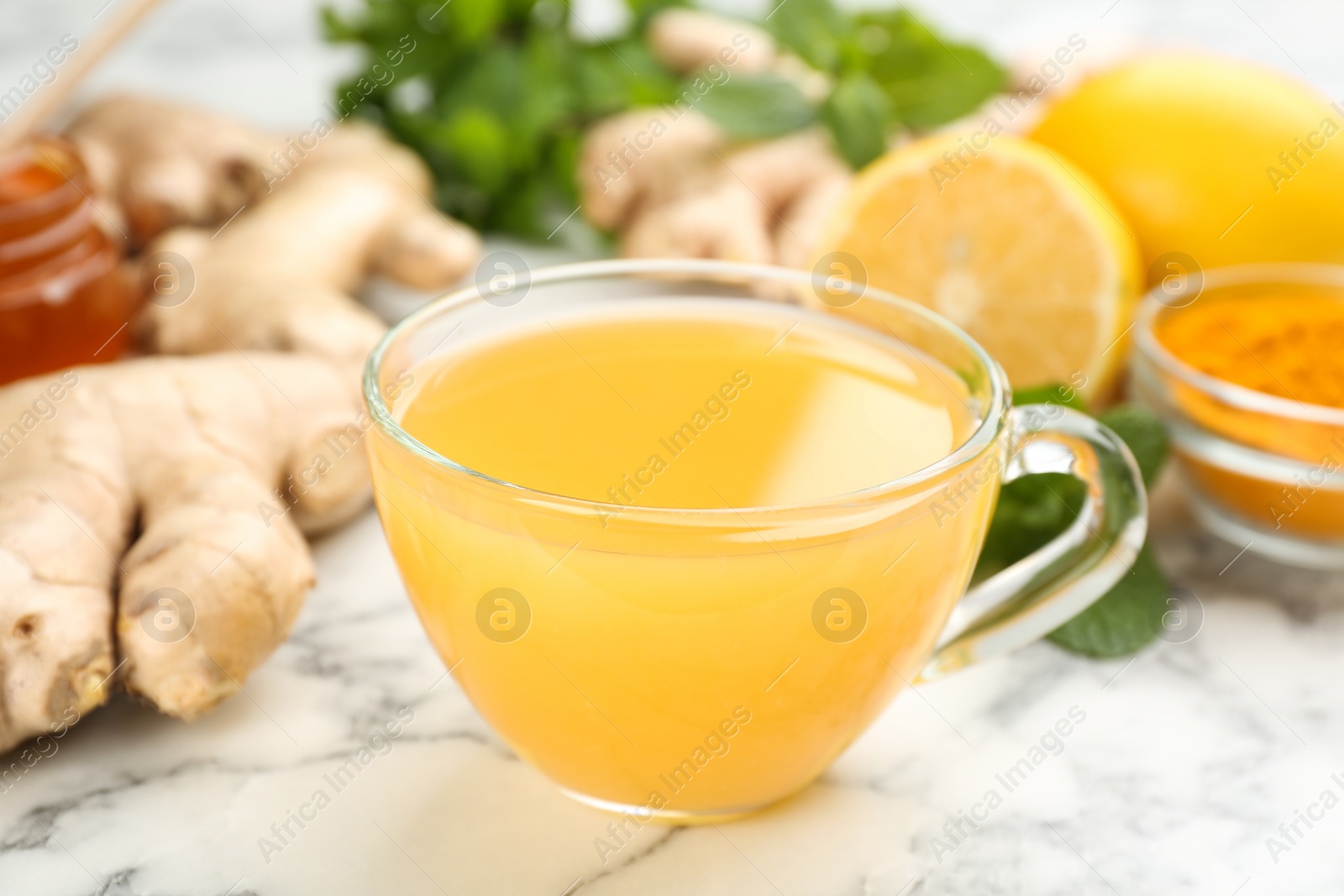 Photo of Immunity boosting drink and ingredients on white marble table, closeup