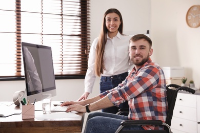Photo of Man in wheelchair with his colleague at workplace