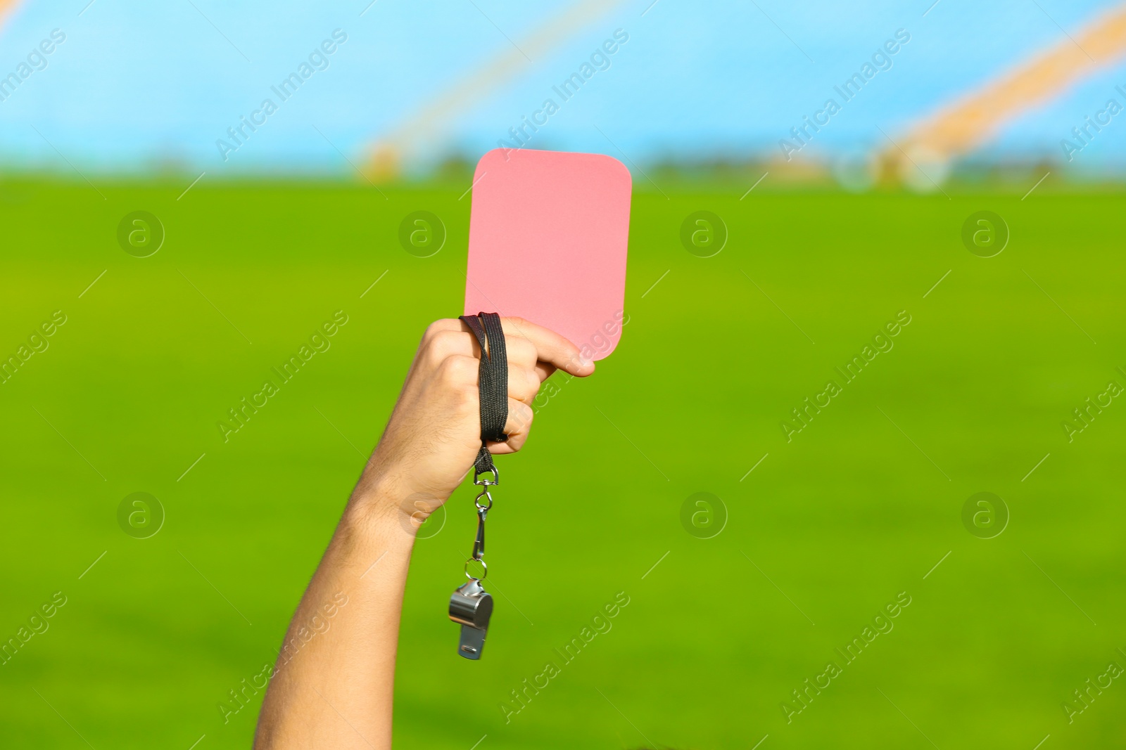 Photo of Football referee holding red card and whistle at stadium, closeup