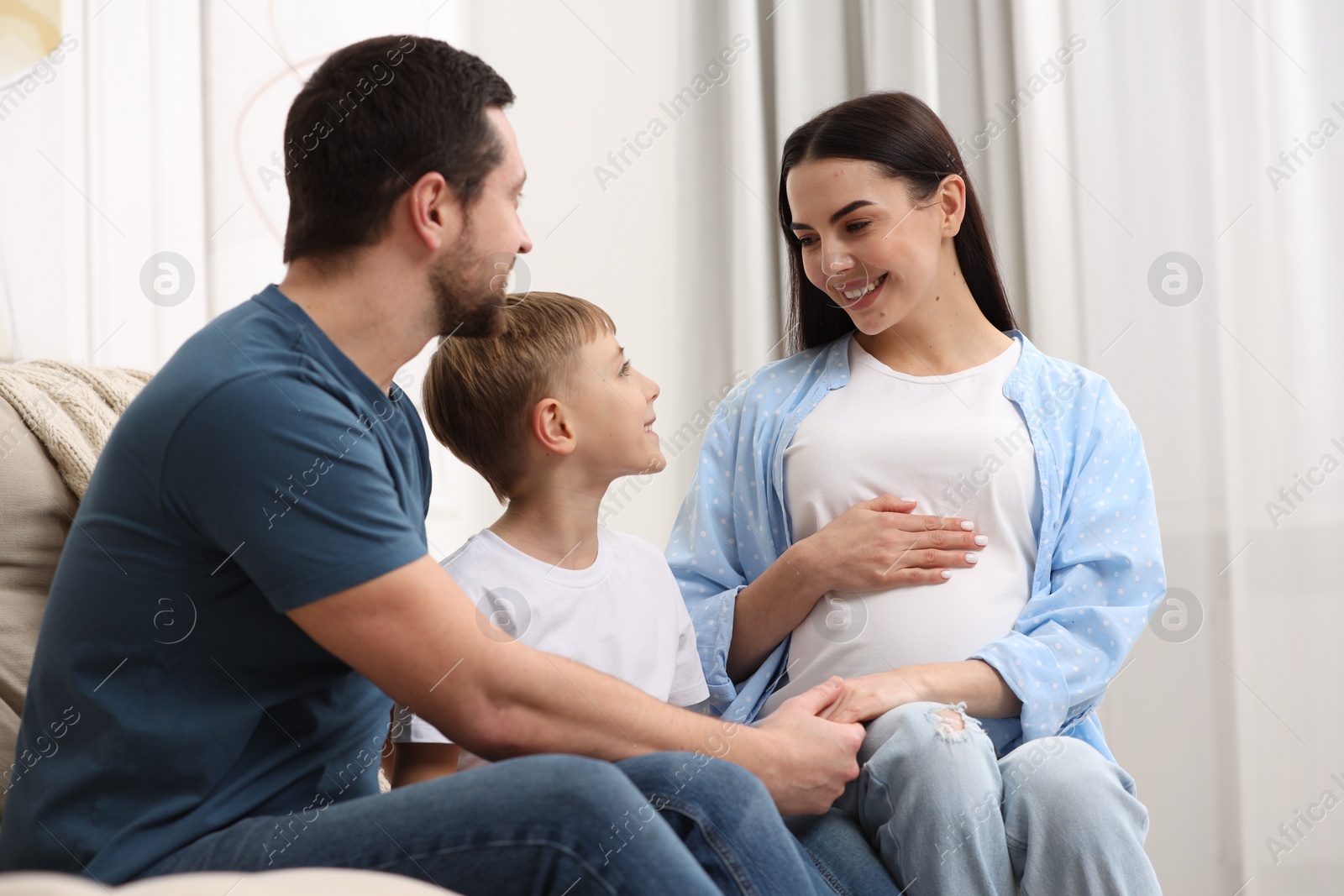 Photo of Pregnant woman spending time with her son and husband at home. Happy family
