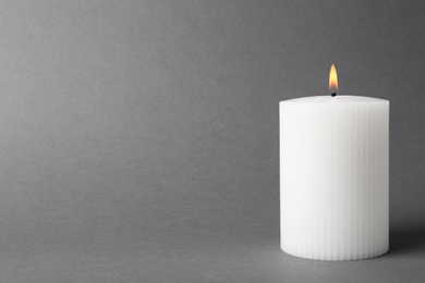 Photo of Burning candle on grey background. Space for text
