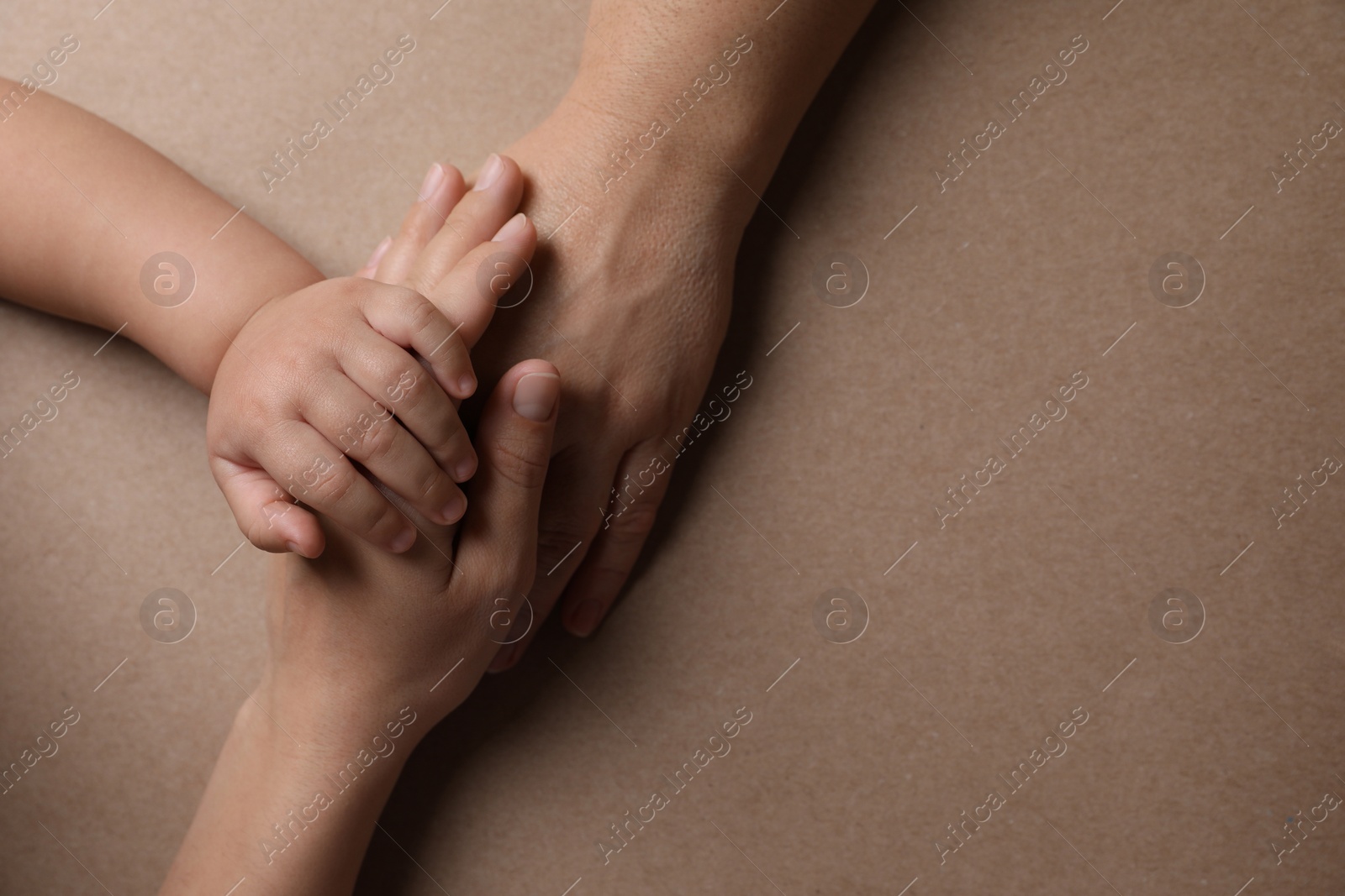 Photo of Family holding hands together on brown background, top view. Space for text