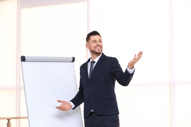 Photo of Young business trainer near flip chart, indoors