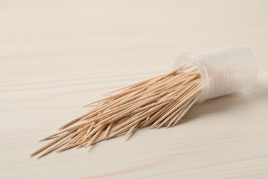 Photo of Disposable toothpicks and holder on white wooden background