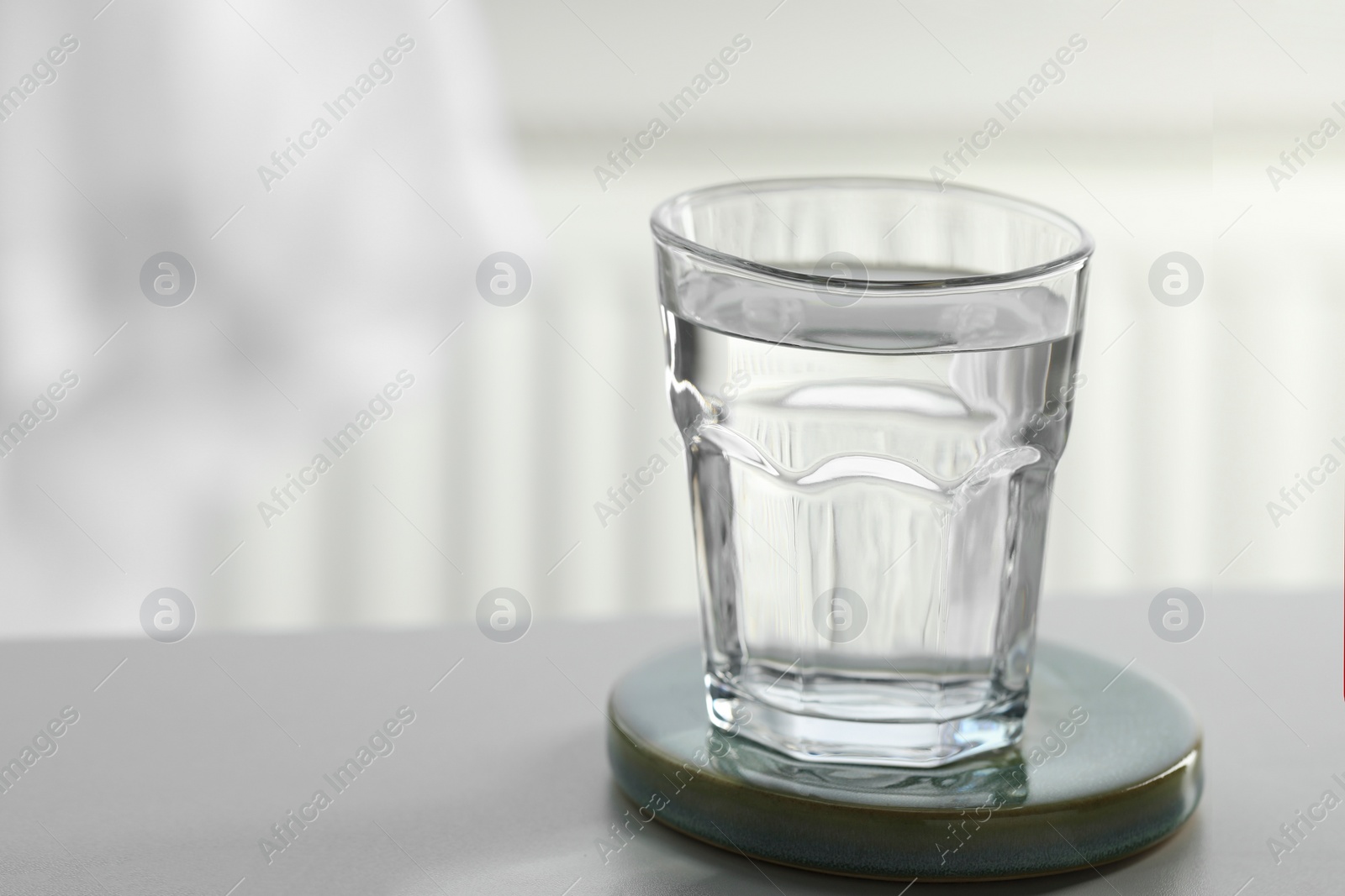 Photo of Glass of pure water on light table against blurred background, space for text