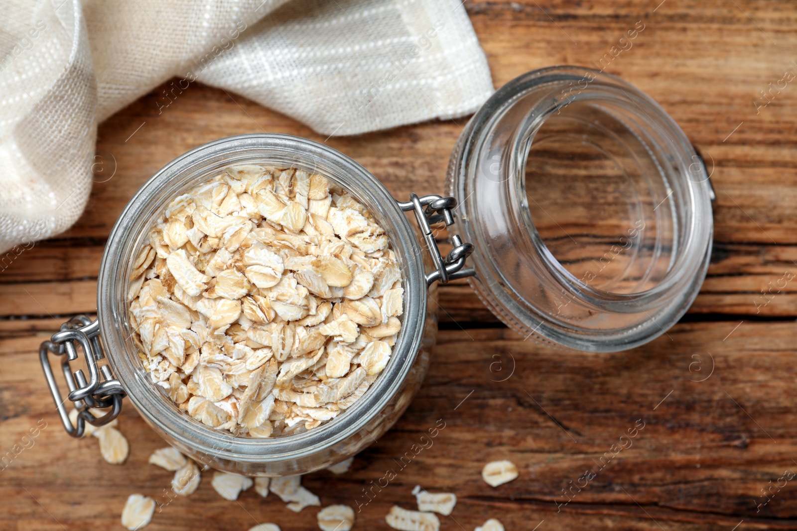 Photo of Glass jar with oatmeal on wooden table, flat lay