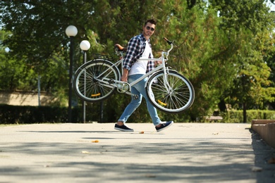 Handsome young hipster man with bicycle in park