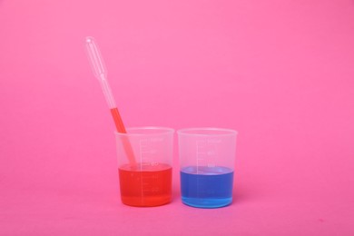 Photo of Beakers with colorful liquids on bright pink background. Kids chemical experiment set
