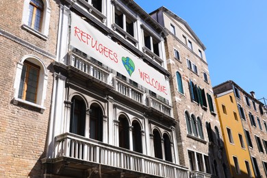 Image of Banner with phrase WELCOME REFUGEES on building outdoors