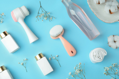 Flat lay composition with face cleansing brushes on light blue background. Cosmetic accessories