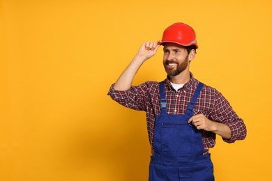Photo of Professional builder in uniform on yellow background, space for text
