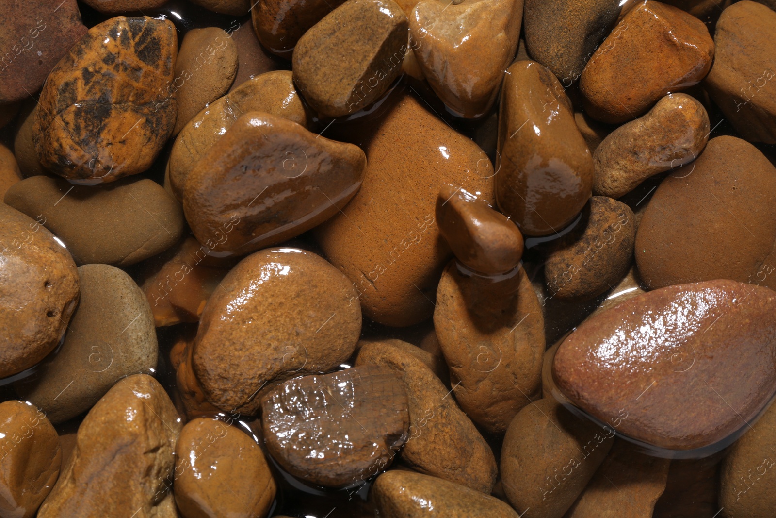 Photo of Beautiful pebbles in water as background, top view