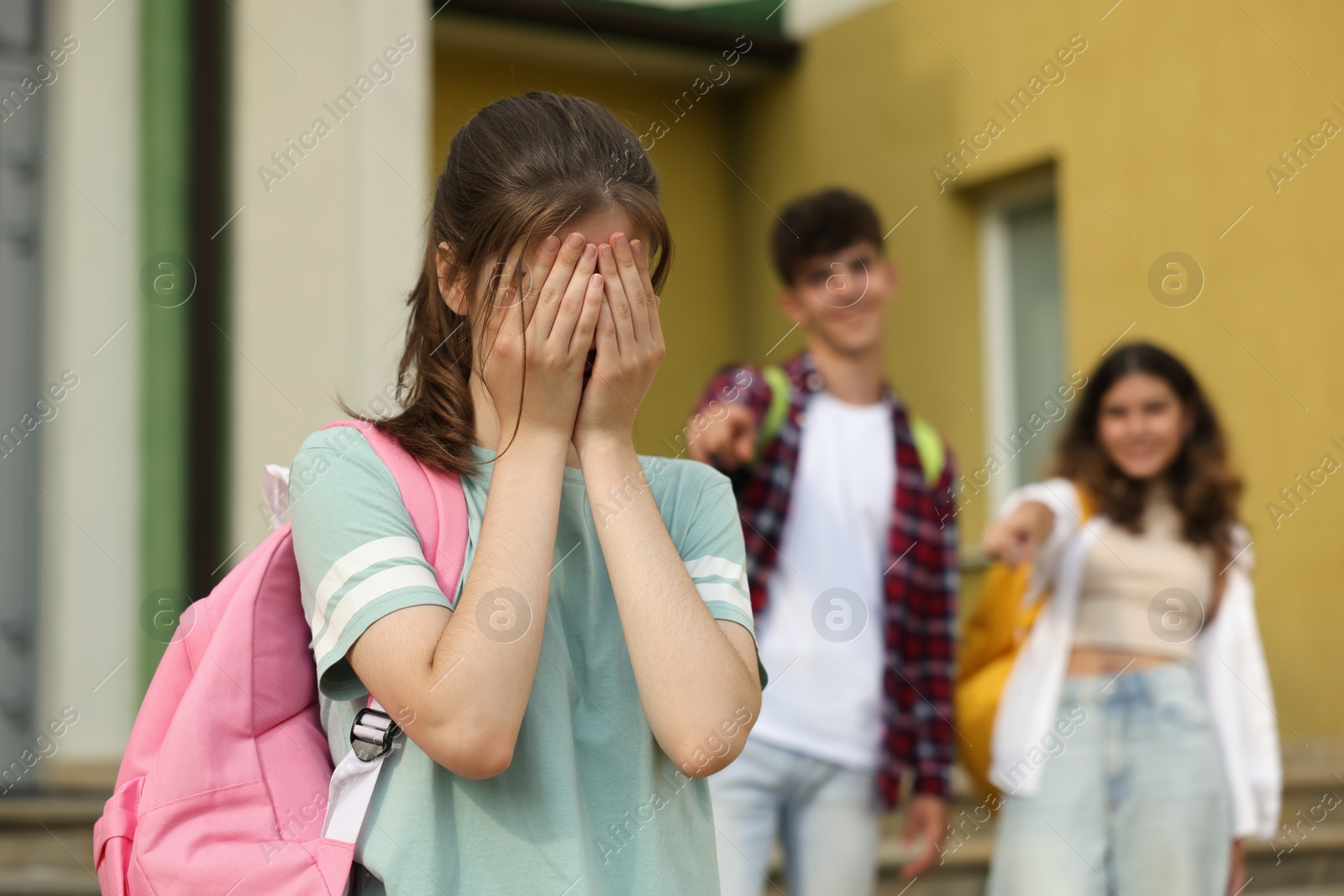 Photo of Teen problems. Students pointing at upset girl outdoors, selective focus