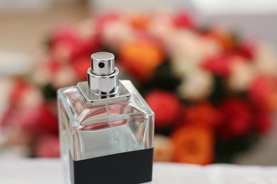 Bottle of perfume against beautiful roses, closeup. Space for text