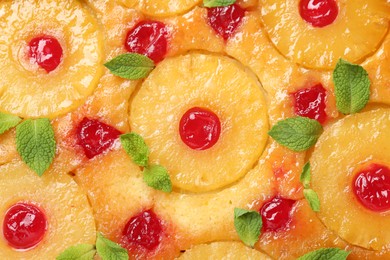 Tasty pineapple cake with cherries and mint as background, top view