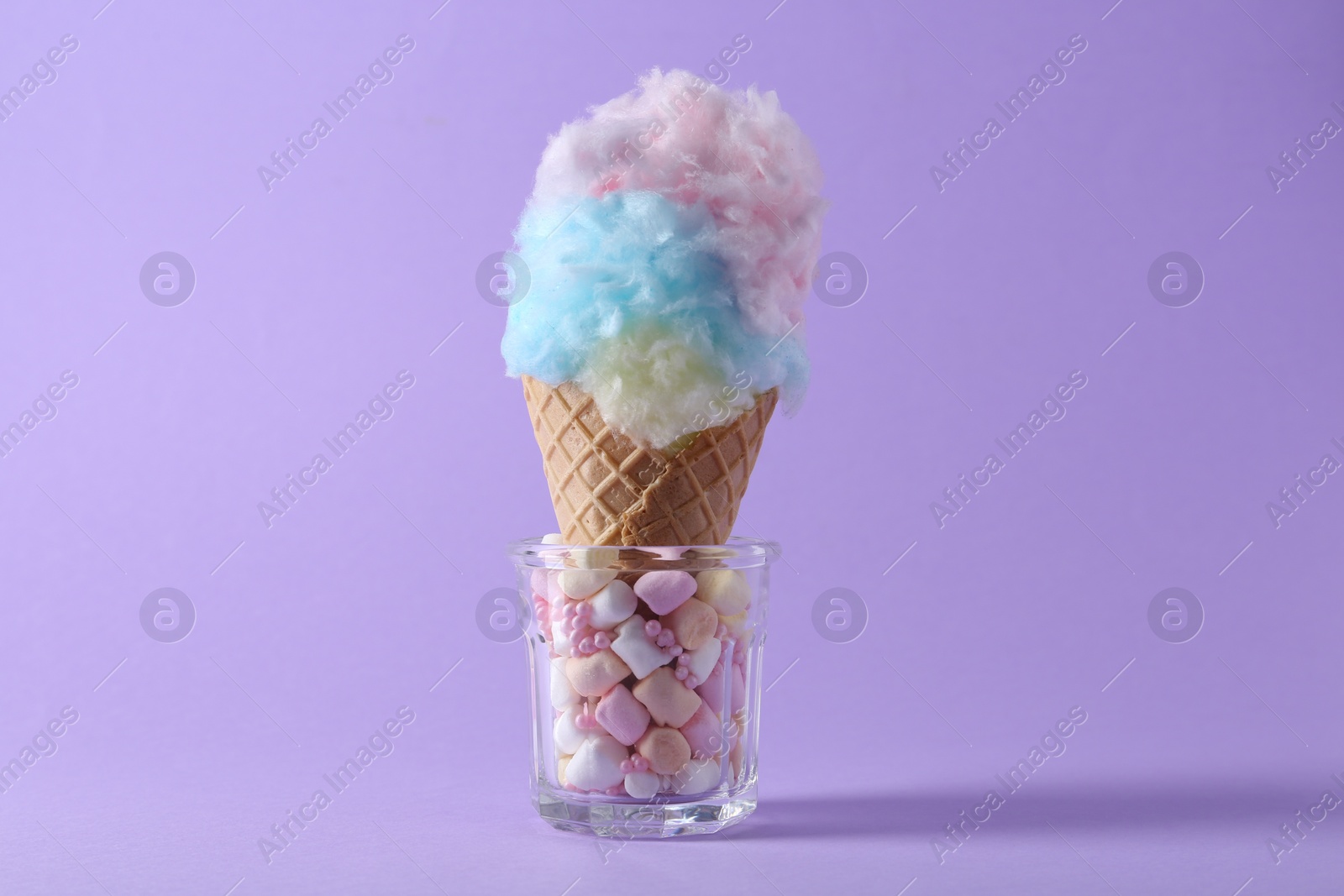 Photo of Sweet cotton candy in waffle cone on purple background