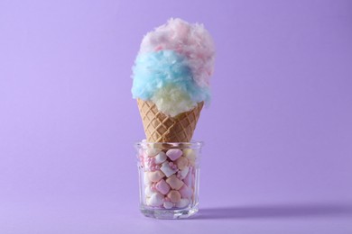 Sweet cotton candy in waffle cone on purple background