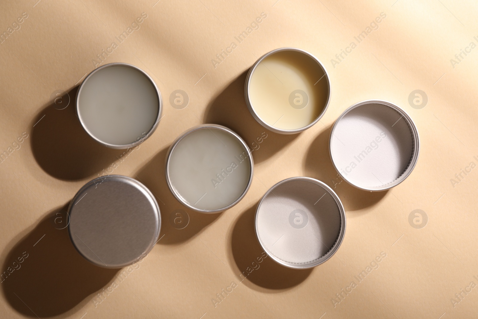 Photo of Different lip balms on beige background, flat lay
