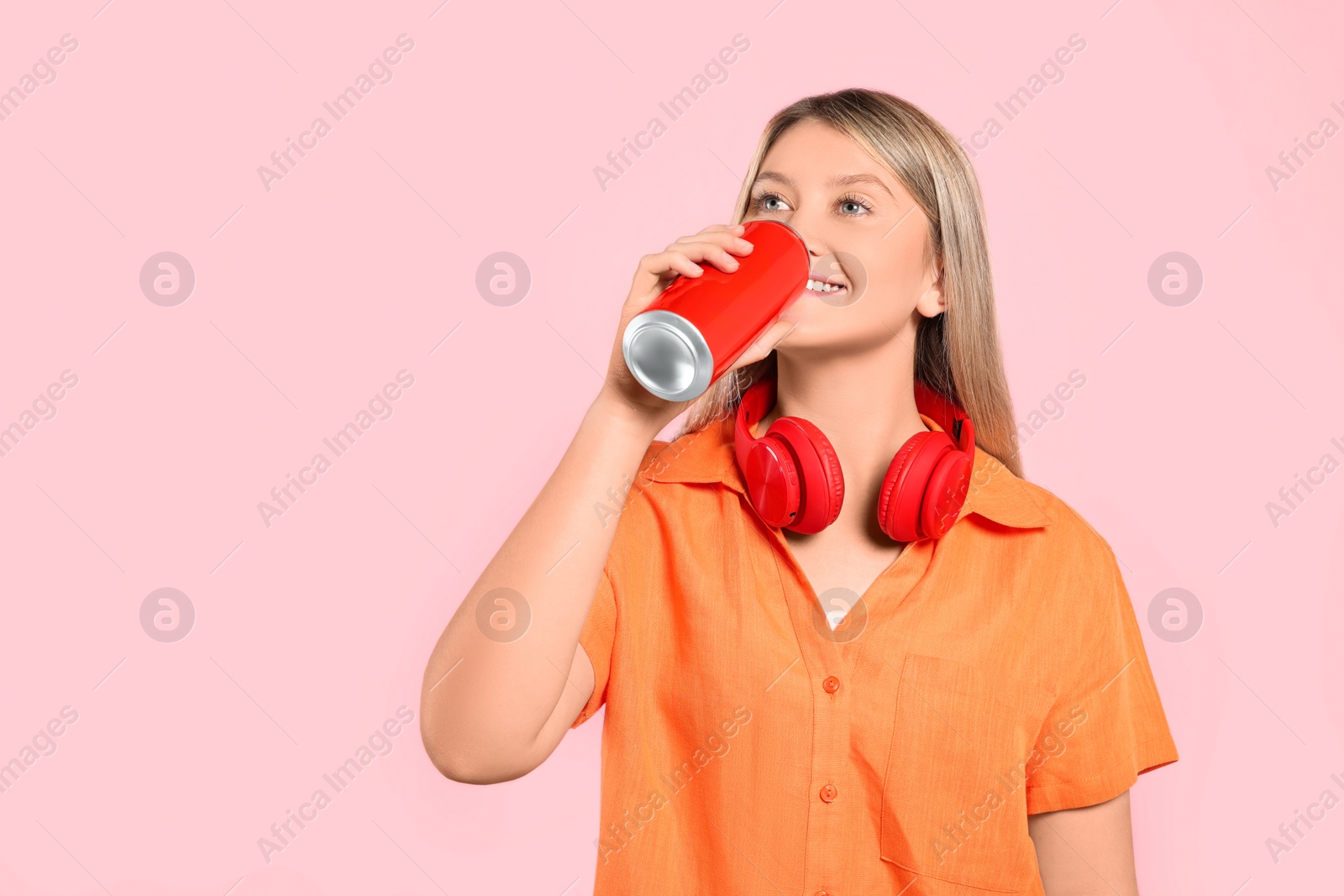 Photo of Beautiful happy woman drinking from red beverage can on pink background