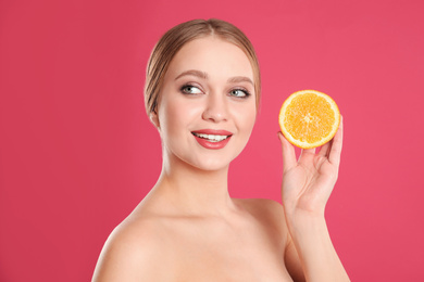 Photo of Young woman with cut orange on pink background. Vitamin rich food