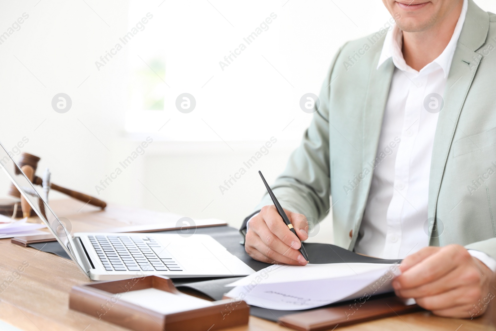 Photo of Male notary signing document at table in office, closeup