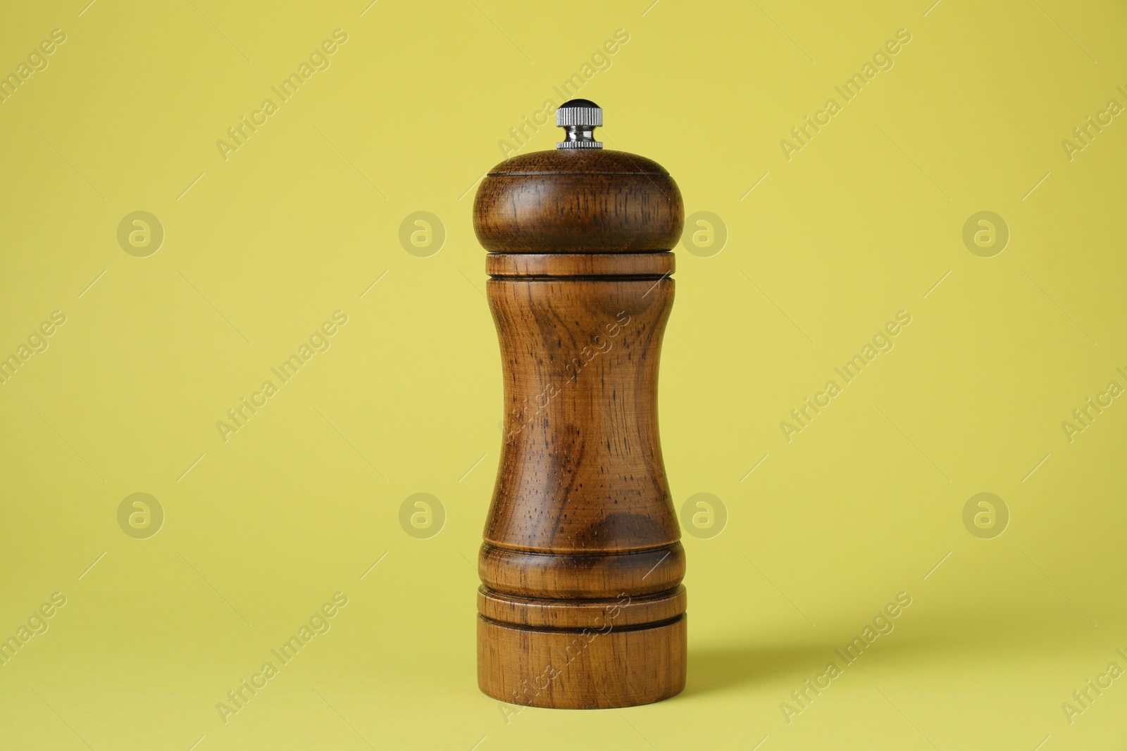 Photo of One wooden shaker on yellow background, closeup