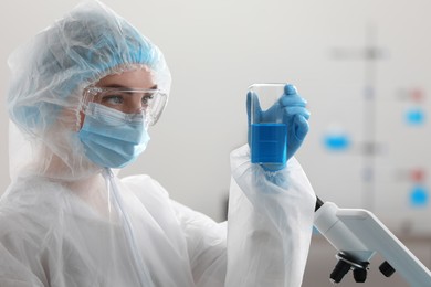 Photo of Young scientist holding beaker with sample in laboratory