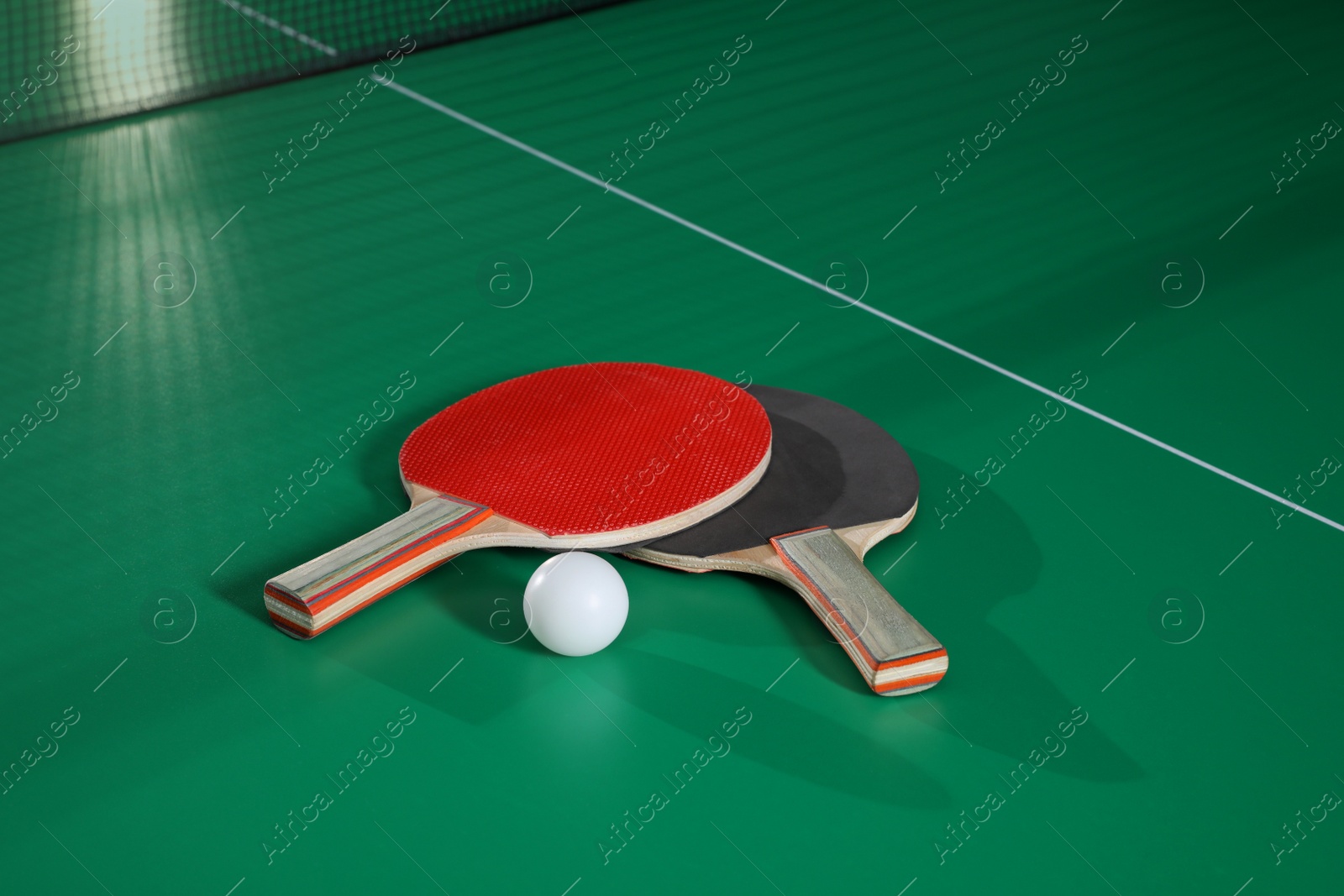 Photo of Rackets and ball on green ping pong table