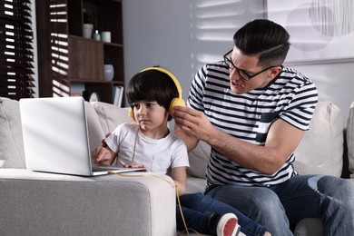 Photo of Internet addiction. Man scolding his son while he using laptop in living room