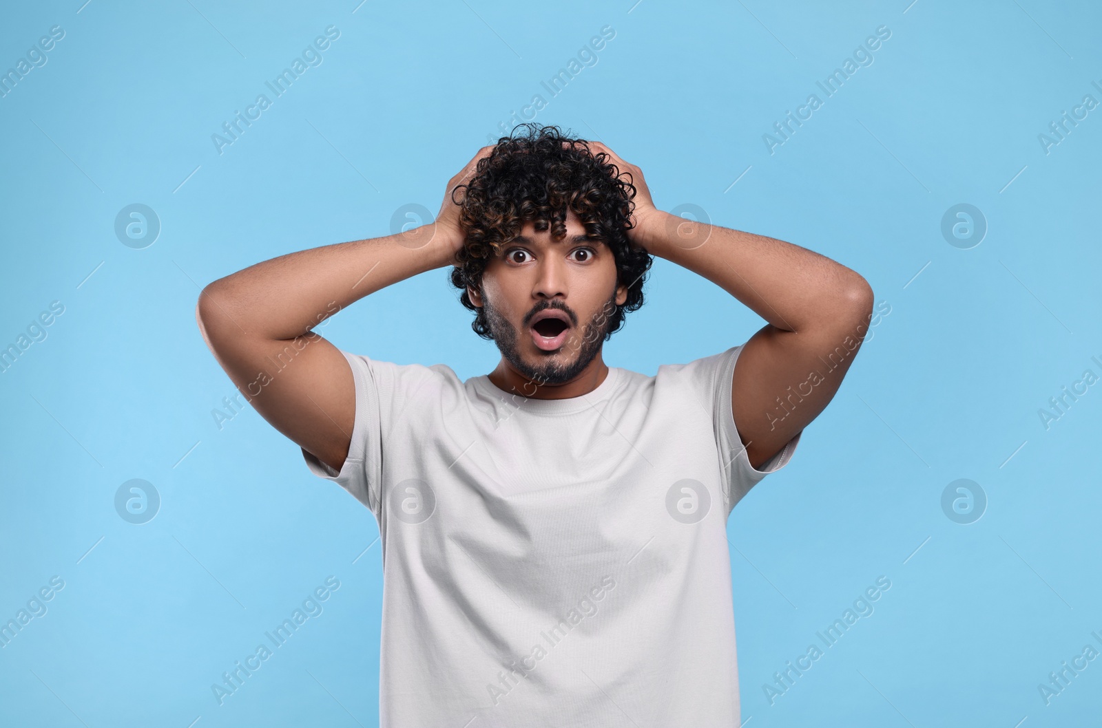 Photo of Handsome surprised man on light blue background, space for text