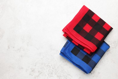 Photo of Folded red and blue checkered bandanas on white background, flat lay. Space or text