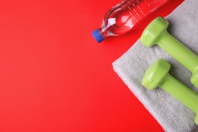 Photo of Vinyl dumbbells, towel and bottle of water on color background, flat lay. Space for text