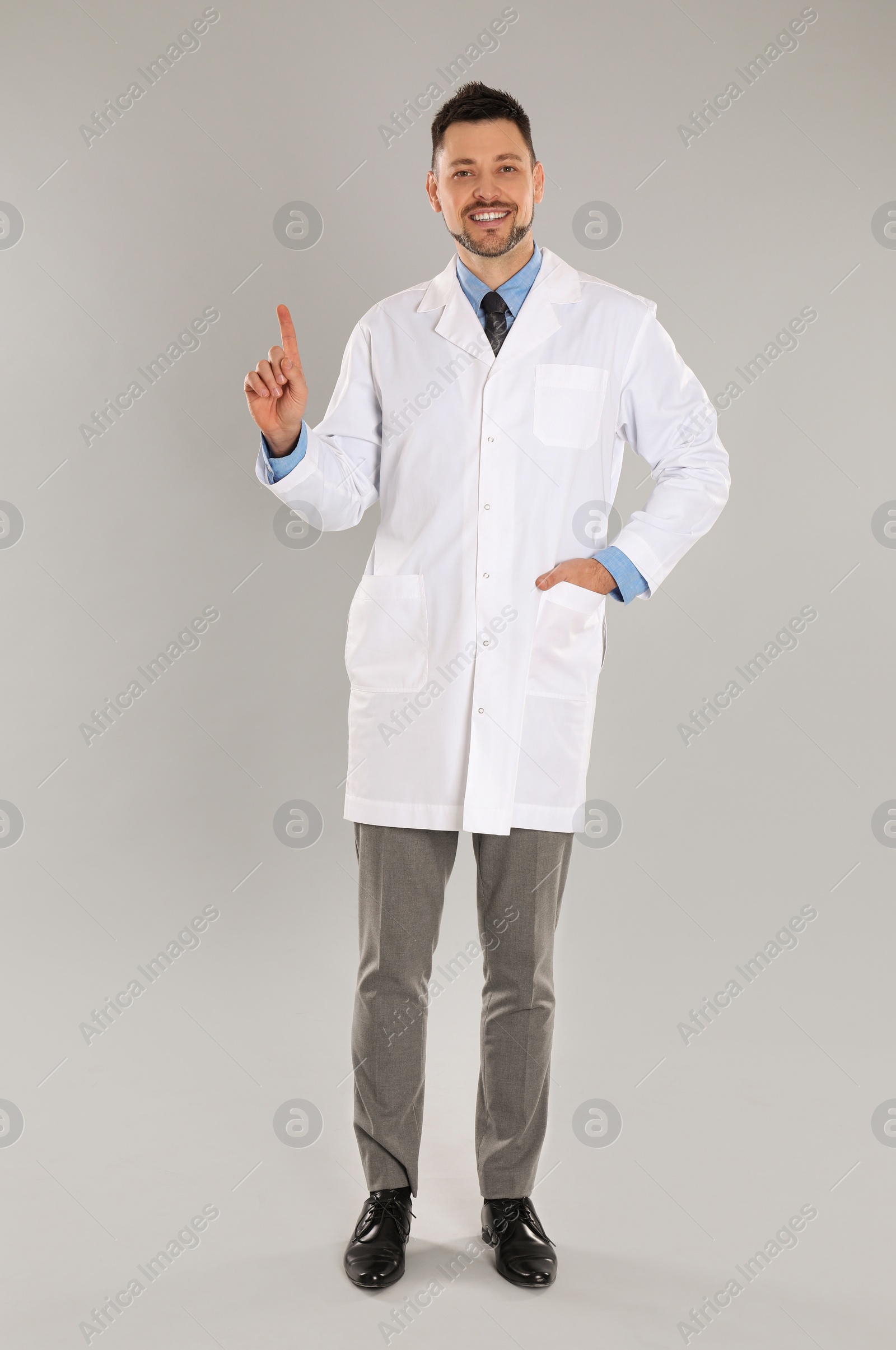 Photo of Happy man in lab coat on light grey background