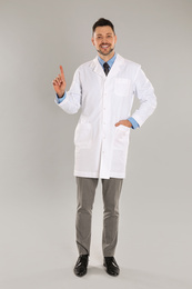 Happy man in lab coat on light grey background
