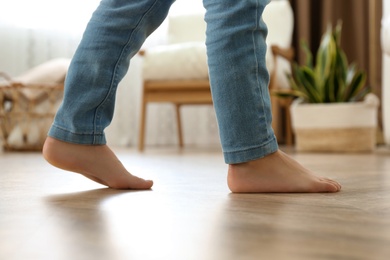 Photo of Little child walking barefoot at home, closeup. Floor heating concept