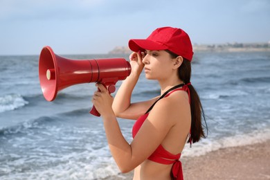 Photo of Beautiful young lifeguard with megaphone near sea