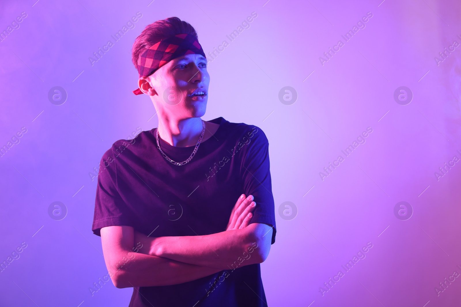 Photo of Stylish young man on color background in neon lights. Space for text