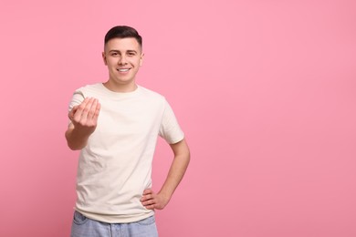 Photo of Handsome man inviting to come in against pink background. Space for text