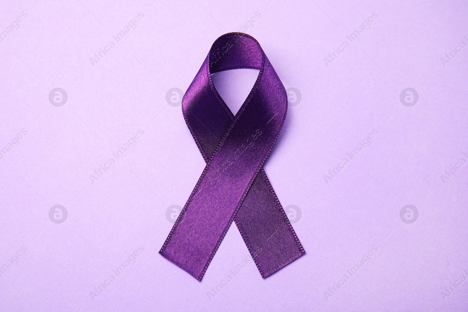 Photo of Purple ribbon on lilac background, top view. Domestic violence awareness