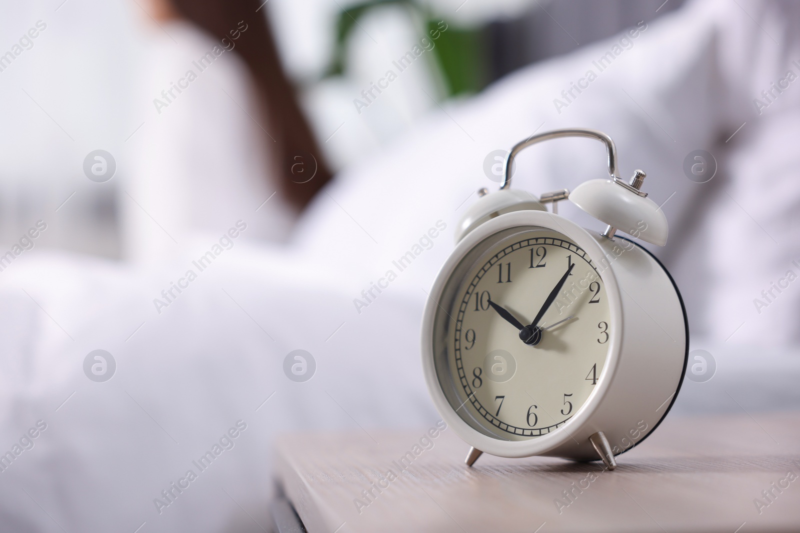 Photo of Alarm clock on nightstand. Woman awakening on bed at home, selective focus