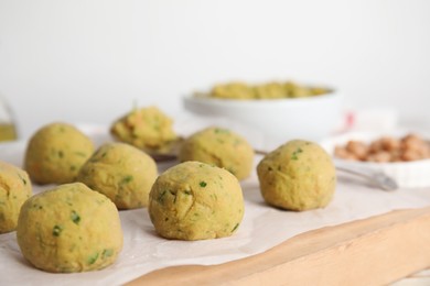 Photo of Raw falafel balls on wooden board, closeup