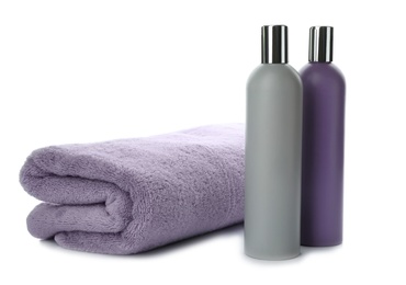 Photo of Folded towel and shampoo isolated on white