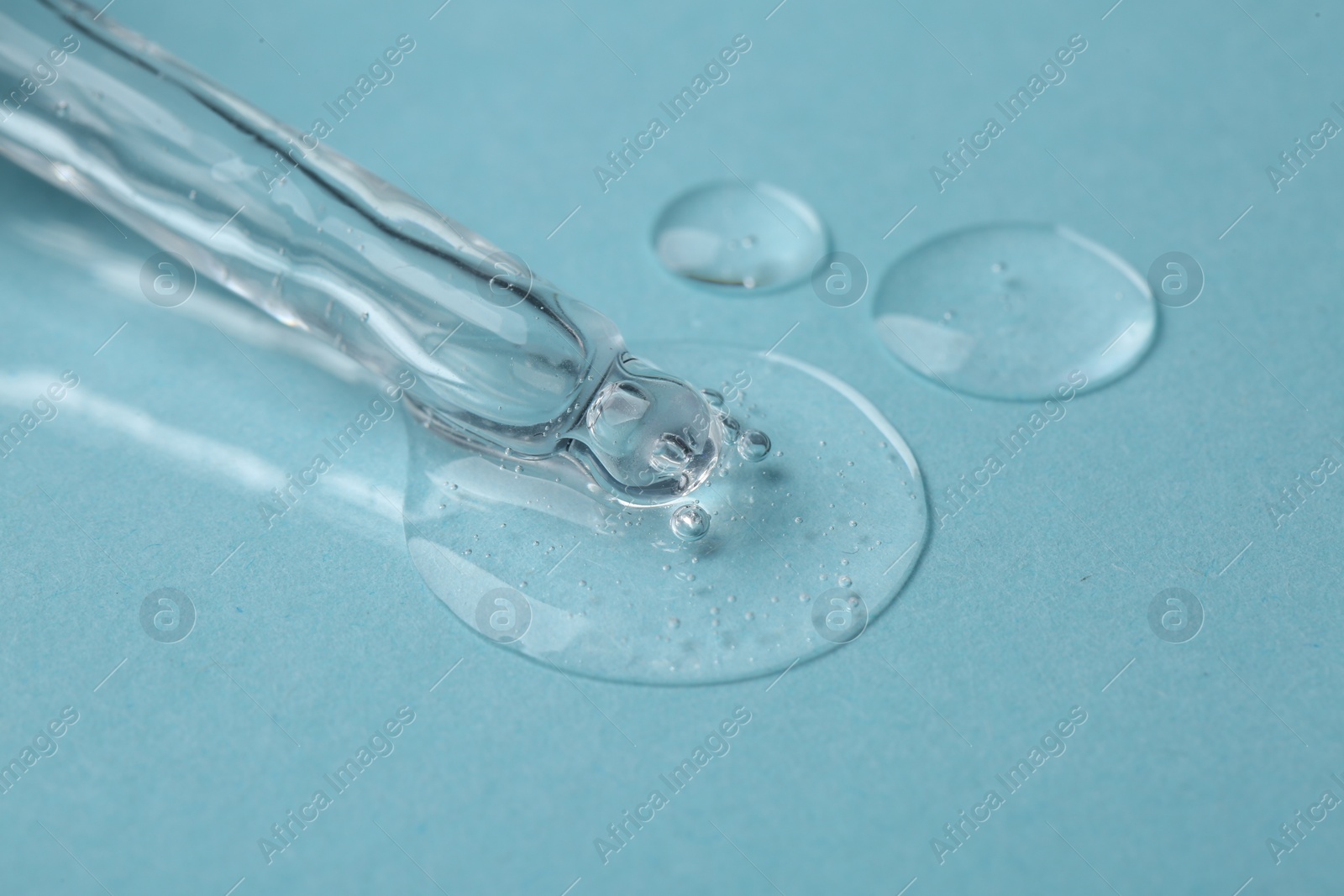 Photo of Pipette with cosmetic serum on light blue background, closeup