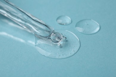 Photo of Pipette with cosmetic serum on light blue background, closeup