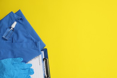 Photo of Flat lay composition with medical uniform and antiseptic on yellow background. Space for text