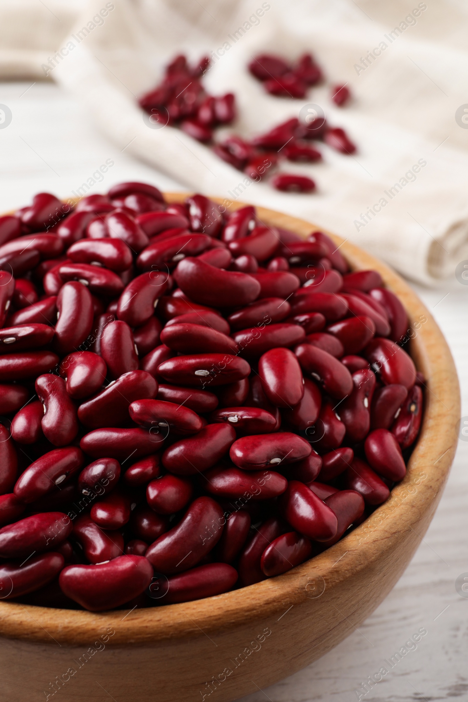 Photo of Raw red kidney beans in wooden bowl on table, closeup