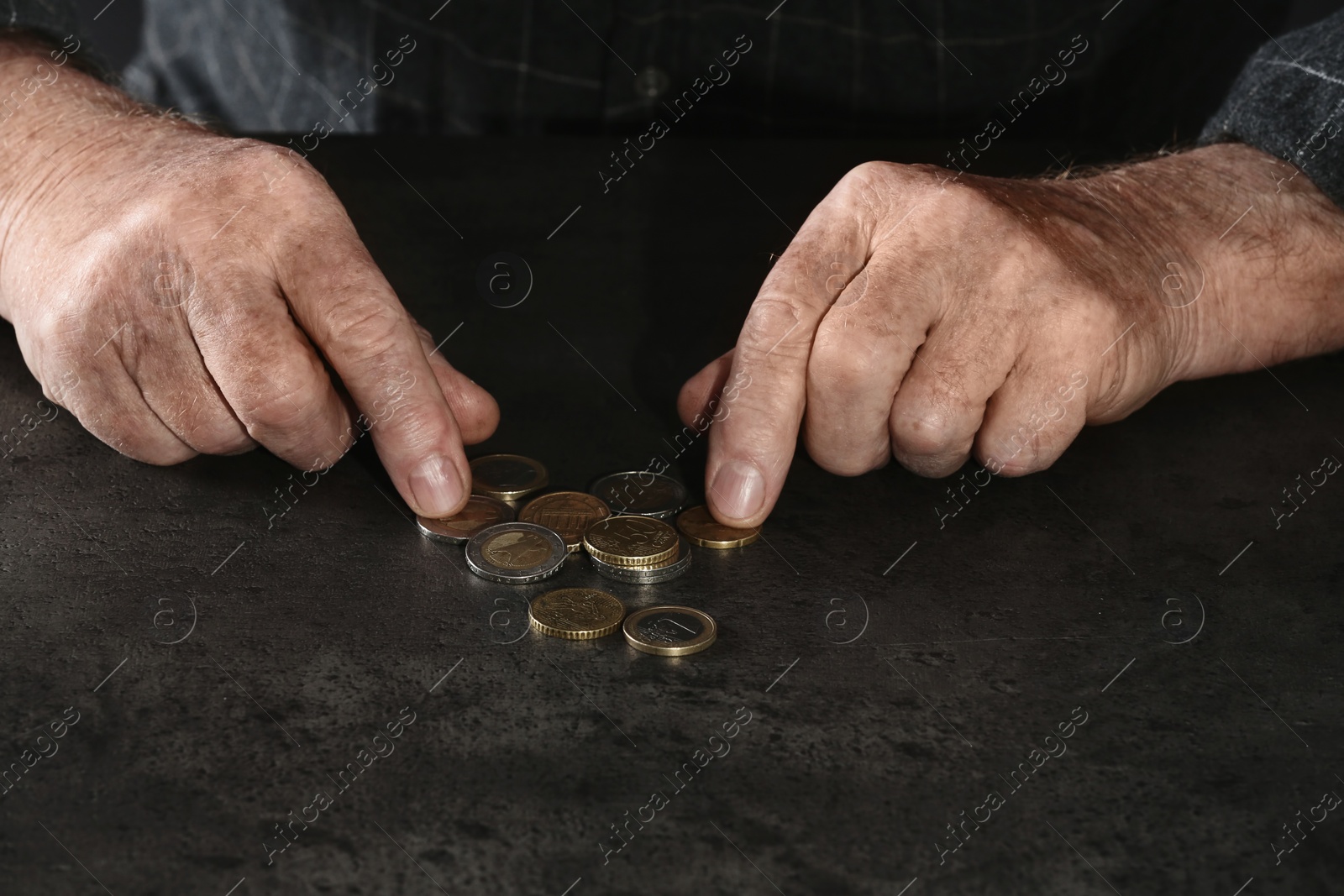 Photo of Poor elderly man counting coins at table, focus on hands