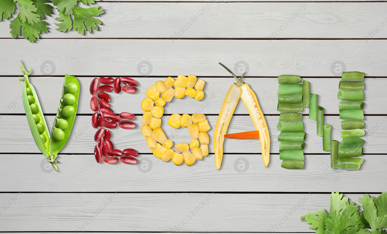 Image of Word VEGAN made of different fresh tasty vegetables on white wooden background, flat lay