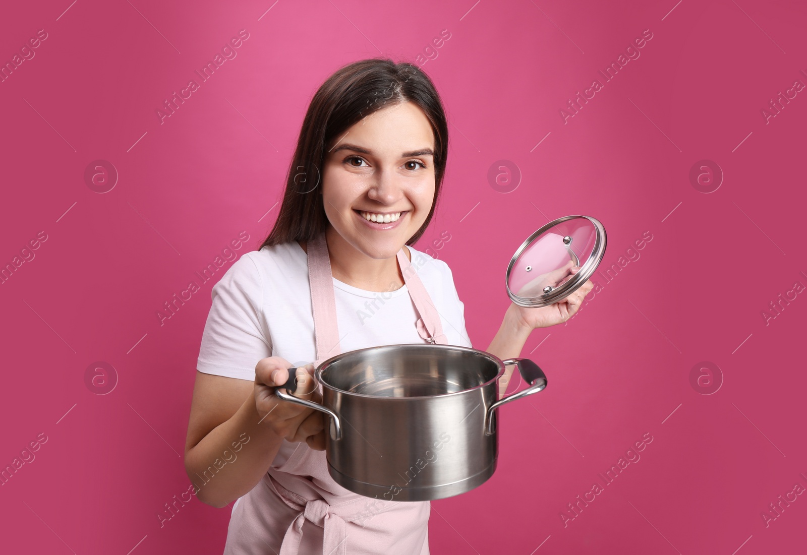 Photo of Happy young woman with cooking pot on pink background